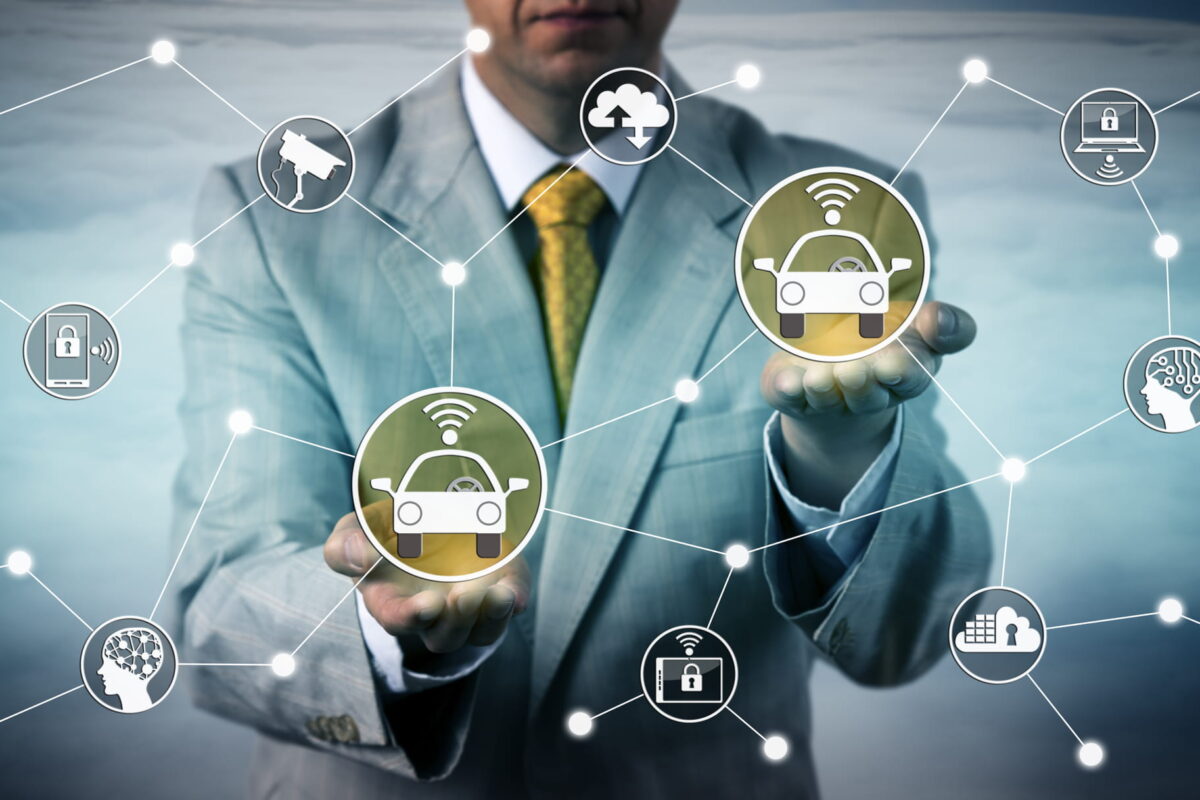 Unrecognizable male enterprise executive connecting two robotic cars via an smart network. Technology concept for vehicle-to-vehicle connectivity, V2V communication, connected autonomous car, IoT.